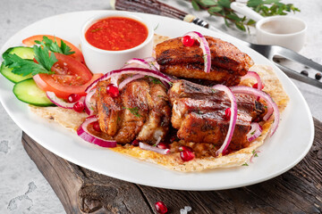 Pieces of pork kebab on a plate with pita bread and fresh vegetables. Grilled Pork Dishes, close up