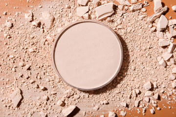 Crushed face powder and round box of pressed one on top on brown background