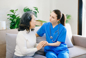 Fototapeta premium Medical doctor holing senior patient's hands and comforting her at home