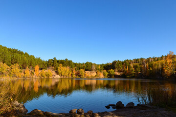 Lake in the autumn forest in the rays of the evening sun