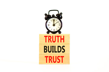 Truth builds trust symbol. Concept words Truth builds trust on wooden blocks on a beautiful white table white background. Black alarm clock. Business truth builds trust concept. Copy space.