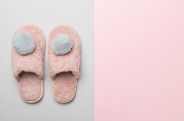 Soft pink slippers on color background, top view