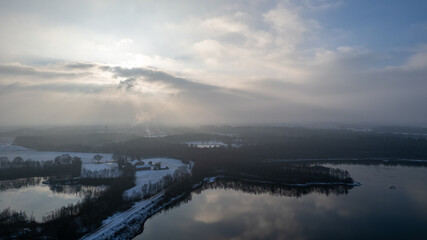 Aerial landscape of the frozen lake and forest in the snow in Belgium at sunset shot by a drone. High quality photo