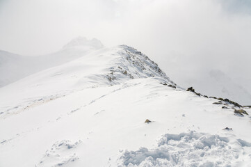 Fototapeta na wymiar Mountain winter Caucasian landscape with a rocky peak in the frame on a cloudy foggy day, ski resort