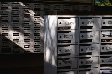 Beautiful sunlight shine on rows of white wooden mailboxes with keyholes for resident in...