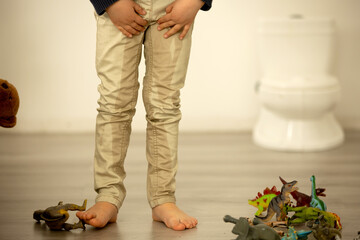 Little toddler child, boy,  pee in his pants while playing with toys, child distracted and forget to go to the toilet - obrazy, fototapety, plakaty