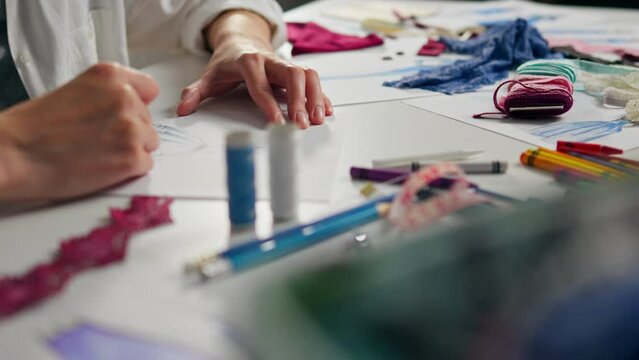 A young fashion designer brings ideas to paper. Fashion designer creating unique clothes Fashion modern. In slow motion Designer confidently creates sitting in design studio, Fashion clothes
