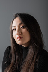 Fototapeta premium portrait of young and asian woman in black turtleneck looking at camera isolated on dark grey