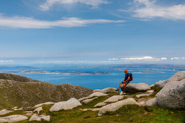 Hiker paused on summit of Goatfell to look at view over Firth of Clyde