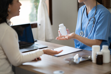 Obraz premium Young female doctor explaining bottle of medicine to her patient.