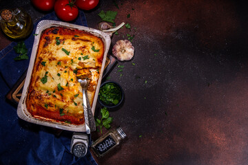 Homemade cannelloni pasta, big tray with haked cannelloni with minced meat with bechamel sauce,with herbs in ingrediant on dark background