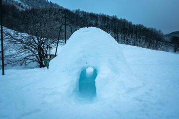 Pequena casa feita de neve a meio da montanha e florestas num dia frio de inverno