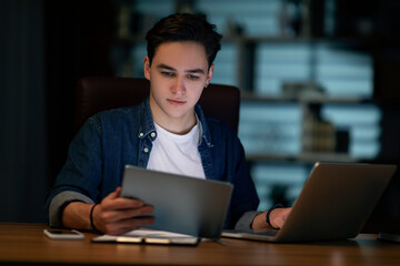 Concentrated young man employee working at office in evening