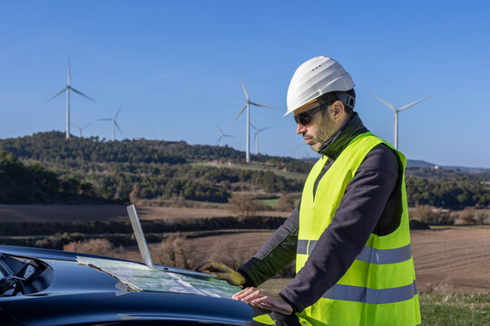 Male engineer examining map on hood of car