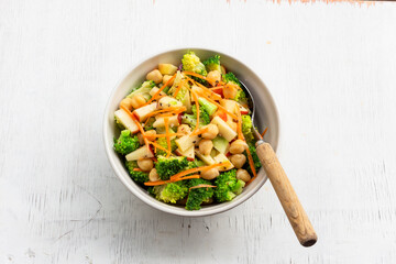 Healthy food broccoli salad add apple chickpeas in white bowl on wood background.