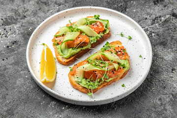 Open sandwiches with salted salmon, guacamole avocado and fresh greens. Delicious breakfast or snack, Clean eating, dieting, vegan food concept. top view.