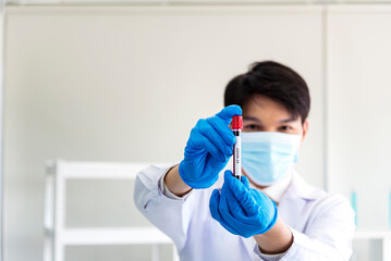 Scientist man holding sample blood test tube in science laboratory. Doctor clinic healthcare technician lab testing blood sample diagnosis. Asian man scientist working in hiv testing medical lab.