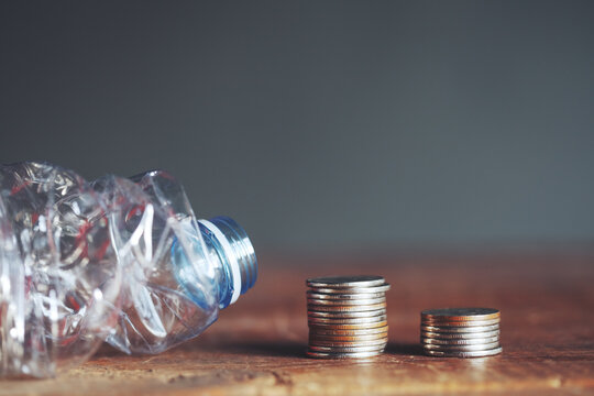 Coins and plastic water bottle on table. Make money on recycling, reusing or reducing plastic concept