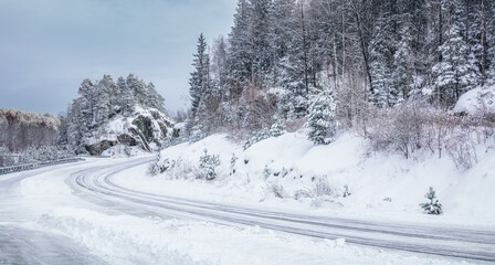 Slipery country road in snowy forest in winter. No cars.Bad driving conditions. Scandinavia.