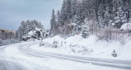 Obraz premium Slipery country road in snowy forest in winter. No cars.Bad driving conditions. Scandinavia.