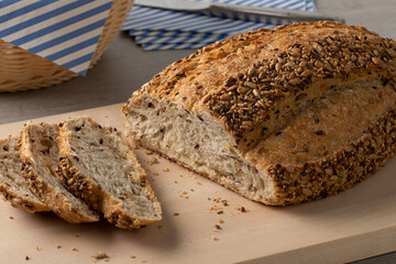 Fresh loaf and slices of country bread,  pain de campagne, and seeds close up on a cutting board 