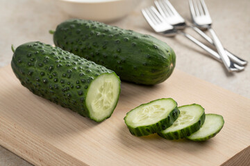 Whole and sliced fresh healthy snack cucumber, Marketmore, close up on a cuttingboard  