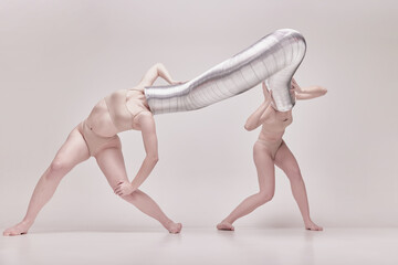 Illusion. Creative photography with two young girls posing in nude underwear over beige studio...