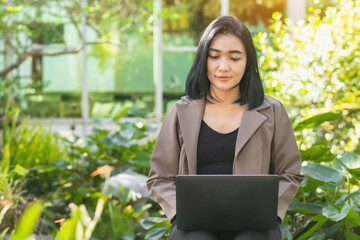 Young beautiful Asian woman working with laptop used the internet and shopped online in the garden, freelancer working businesswoman lifestyle concept