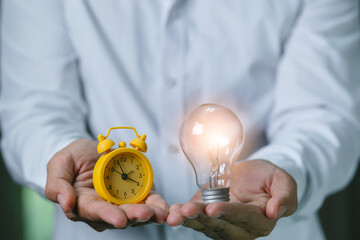 Man holding  light bulbs with clock alarm, concept time manage of good ideas  for working business...