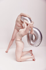 Manipulation. Creative photography with two young girls posing in nude underwear over beige studio...