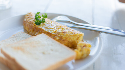 Delicious scrambled eggs on top with parsley and bread in a white plate on  wooden table