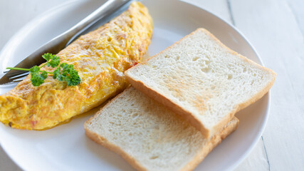Delicious scrambled eggs on top with parsley and bread in a white plate on  wooden table