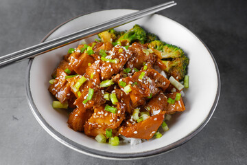 Chopsticks with Delicious sweet chopping chicken rice, sesame seeds, sliced spring onions, broccoli, and vegetables. Asian food, Japanese food.