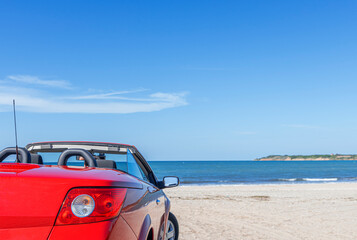 Red car on a sandy beach on a summer day.