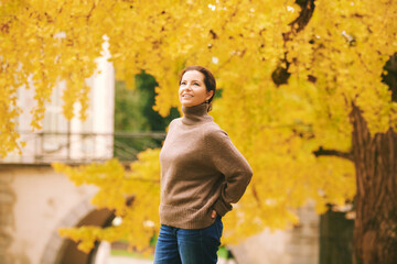 Outdoor portrait of beautiful woman in autumn park, wearing cozy brown turtle neck pullover