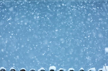 viele neue Schneeflocken fallen auf Zaun blauer Hintergrund