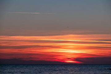 Panoramic sunset view from Sveti Stefan at Adriatic Mediterranean Sea, Budva Riviera, Montenegro, Europe. Reflection of sun beams on water surface. Summer vacation atmosphere. Sky is on fire