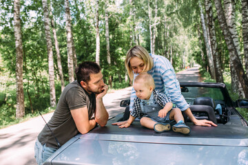 Mom, dad and little son in a convertible car. Summer family road trip to nature
