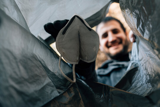 Boy In A Garbage Collection Depositing A Mask In A Garbage Bag Photographed From The Inside