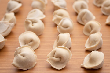 Fototapeta na wymiar Frozen uncooked dumplings pelmeni on a wooden board