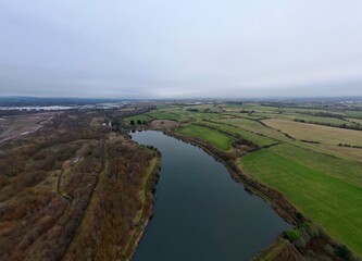 Aerial view looking down onto a lake surrounded by trees and green fields. Taken in Bury Lancashire. 