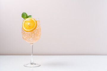 Orange drink with ice in glass on light background. Refreshing tropical summer fruit lemonade or alcoholic drink with orange slice