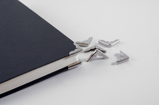 close up of after market book corner protectors clamps pinch close onto corners for added durabillity and stylish accessories isolated on white bacground