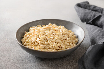 Pasta Cavatelli in bowl on gray background. Close up. Copy space. Raw dry pasta special shape.