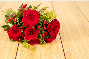 Bunch of red roses on wooden background. Bridal bouquet of bunch of roses lying on wooden background with copy space. 