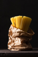 Bunch of spaghetti in craft paper bag on antique table.