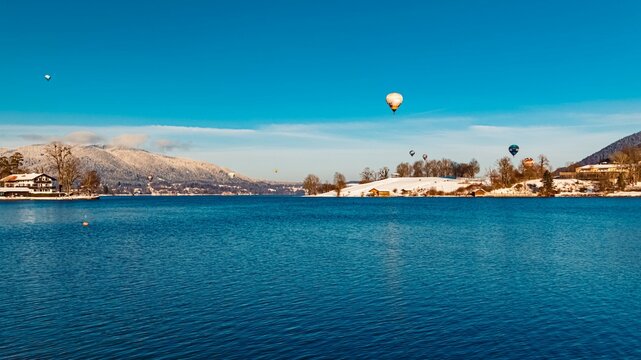 Beautiful alpine winter view with hot air balloons during the Montgolfiade Tegernsee 2023 at Rottach Egern, Bavaria, Germany
