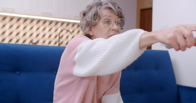 Old lady sits on a couch and turns on TV , 4k