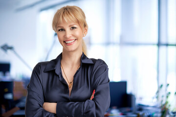 Confident businesswoman standing at the office with folded arms