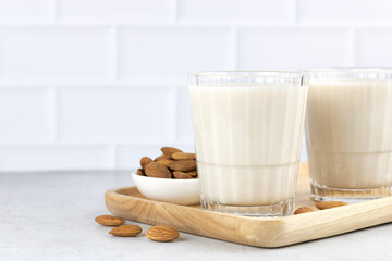 Almond milk in a glass on a white table and almond kernels. Copy Space. Almonds and milk. Lactose free nut milk.